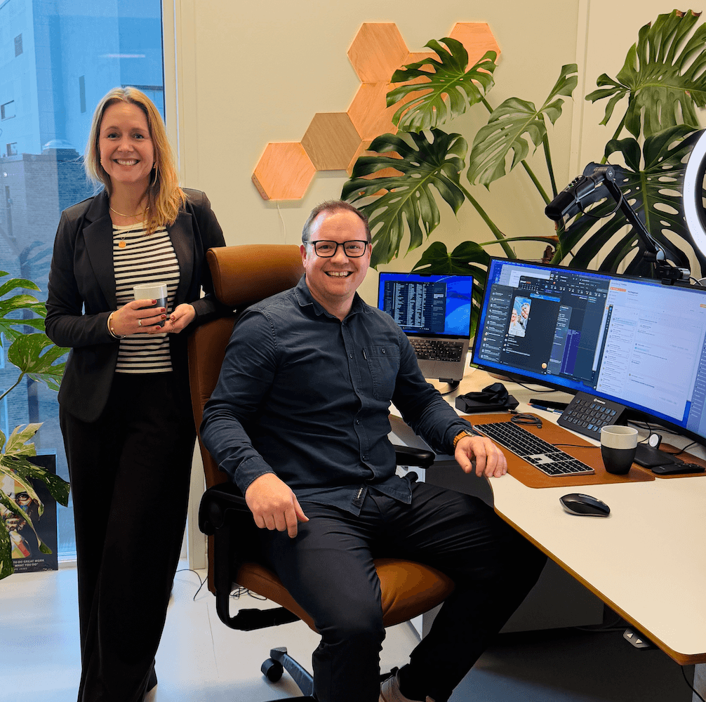 A person standing and one sitting and smiling