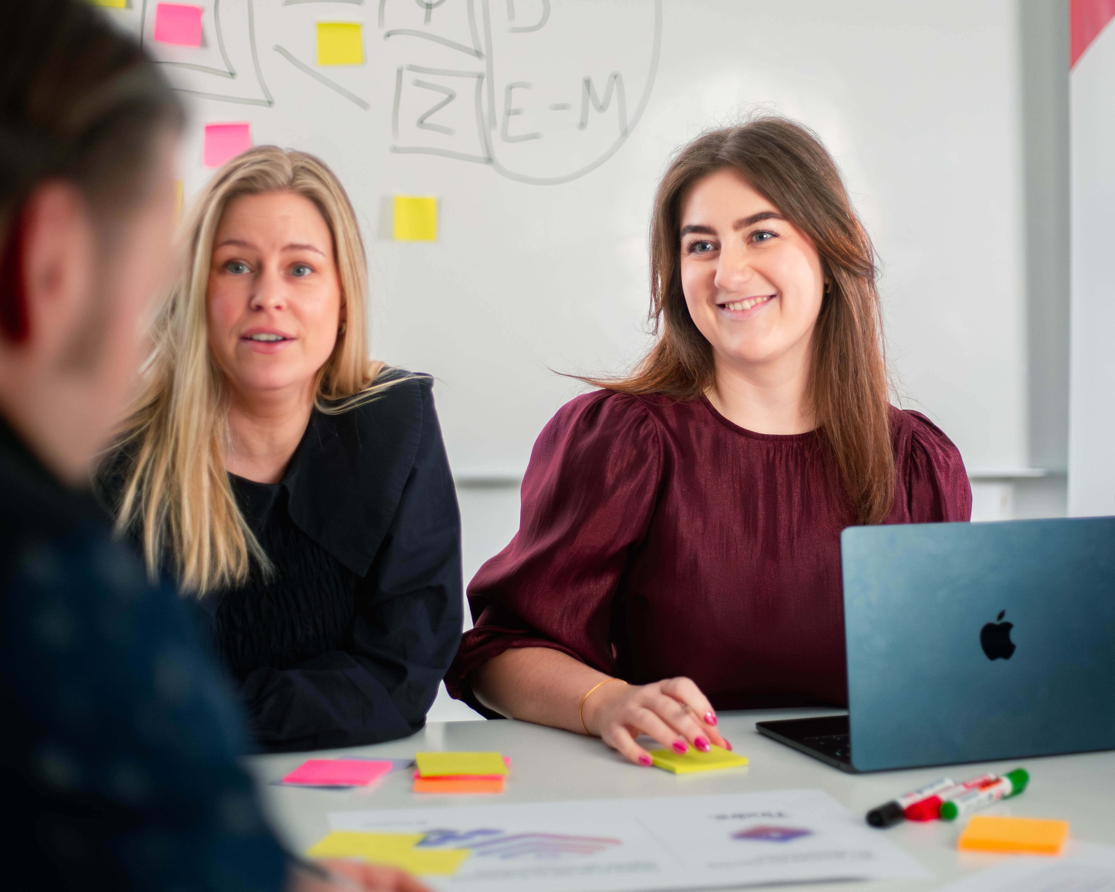 Frontkom colleagues in a meeting, two women smiling with a laptop on the table