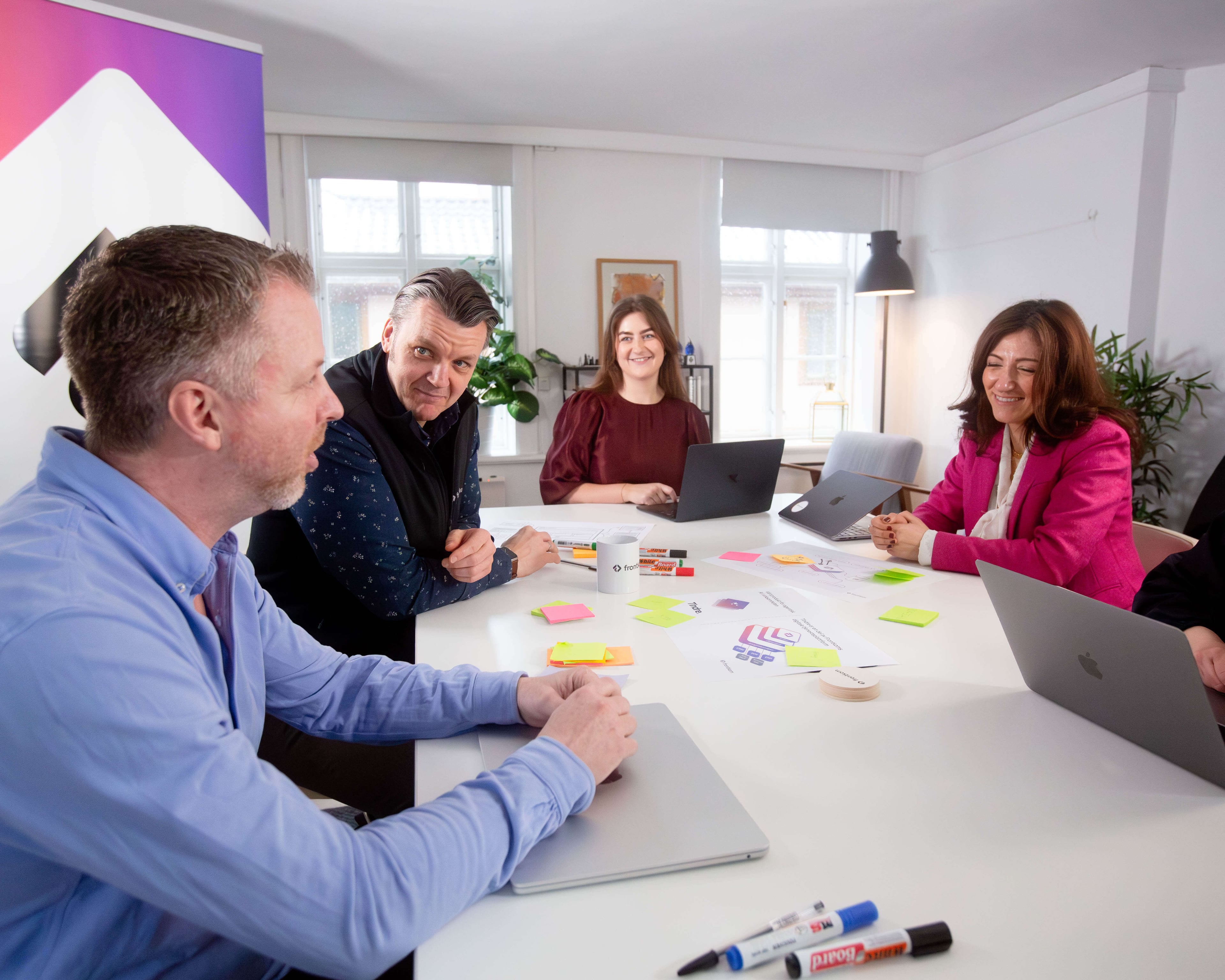 The Frontkom team in a meeting around a table with post-it notes and laptops